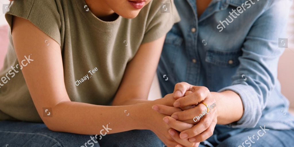 Image of an adult leaning into a younger adolescent and holding hands